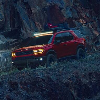 2027 Honda Passport TrailSport Elite in Radiant Red Metallic II front parked on a steep rocky (Mid-Size SUV).