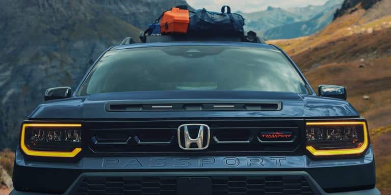 2027 Honda Passport TrailSport Elite in Smoke Blue Pearl front parked in the mountains with gear on the roof (Mid-Size SUV).